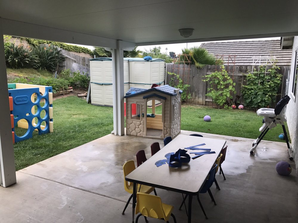 The covered patio, child-sized table and chairs, playhouse and climbing toys in Gemma's fenced backyard
